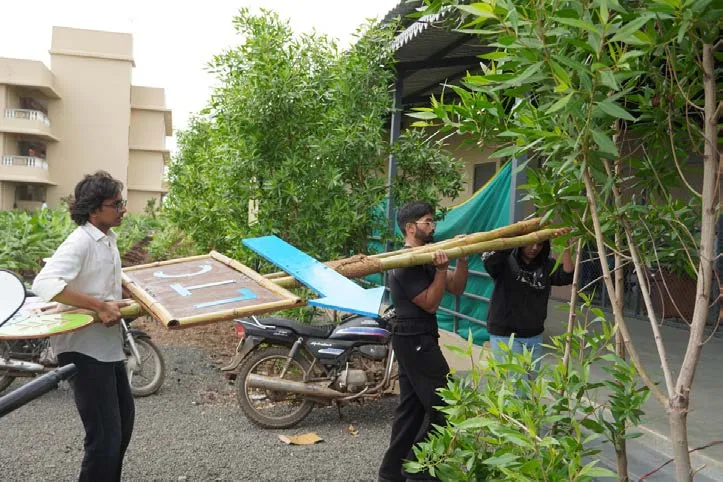 Interns carrying bamboo and finished panels across the site