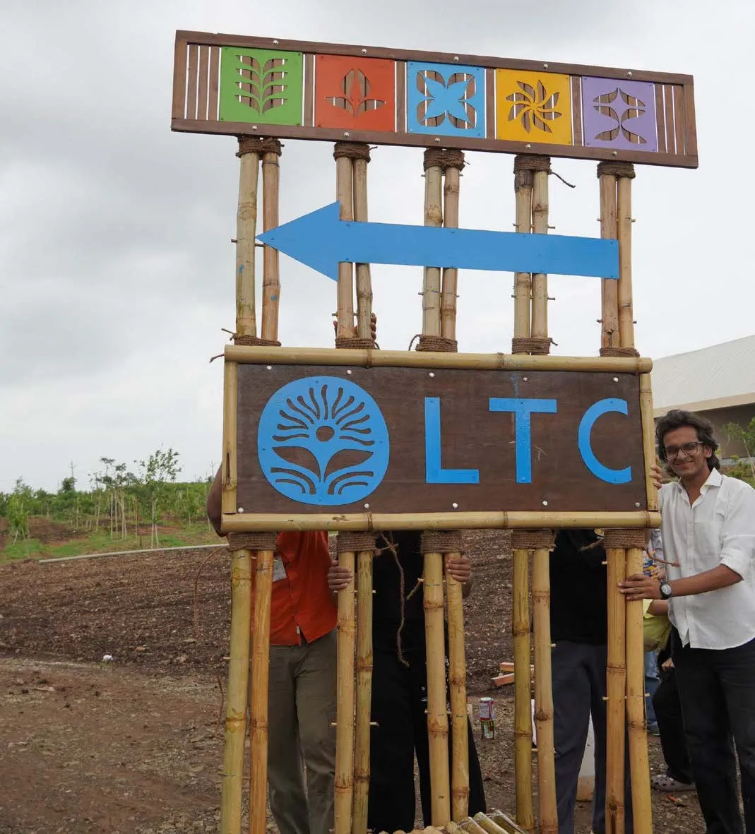 A bamboo wayfinding gateway with five coloured pillar symbols, a blue arrow and the LTC board