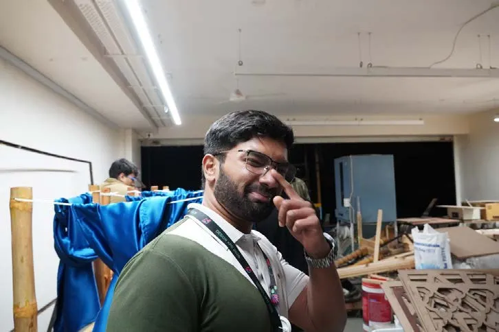 An intern in the workshop among bamboo poles and cut panels