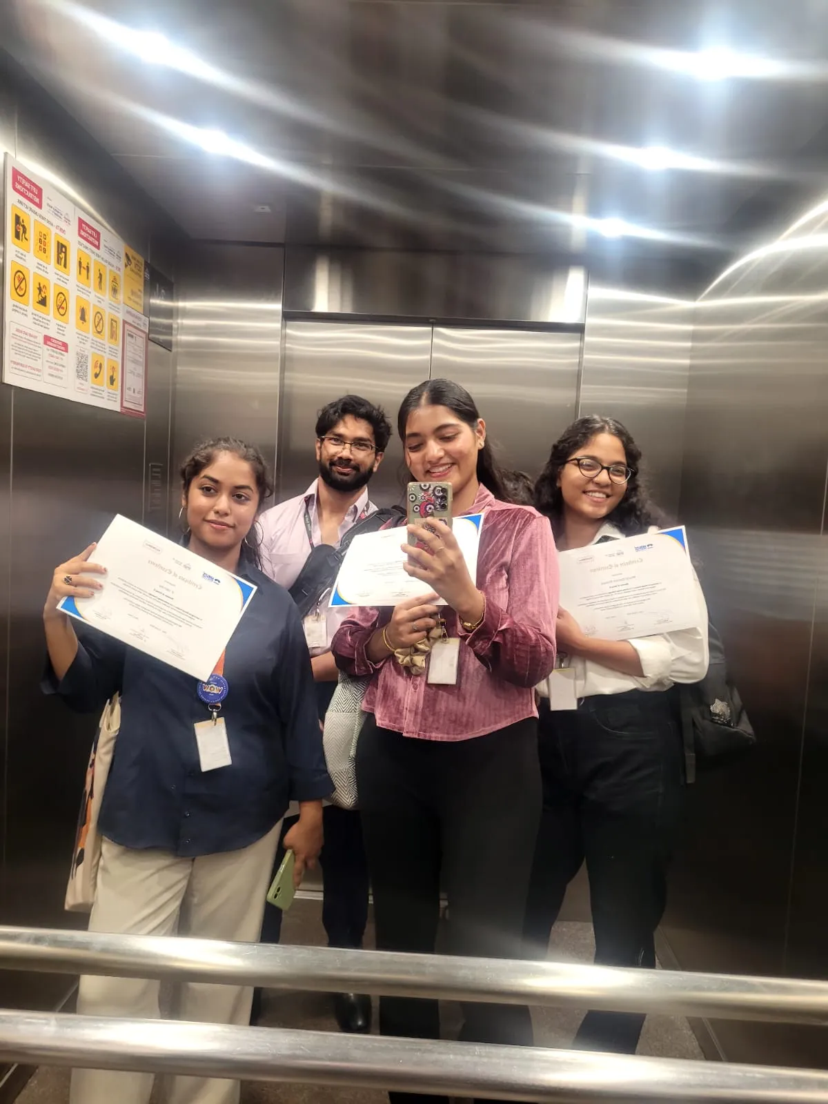 Team Vayu holding their certificates in a lift mirror selfie